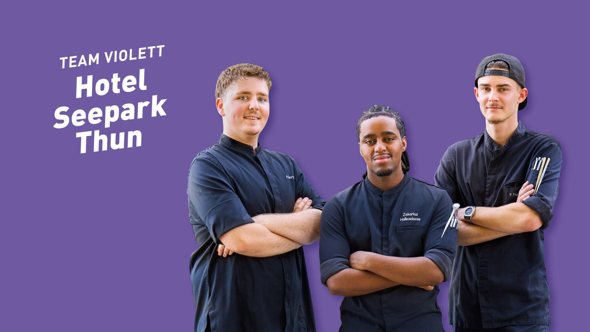 Drei junge Köche in schwarzen Uniformen posieren vor einem violetten Hintergrund, auf dem der Schriftzug Team Violett Hotel Seepark Thun zu lesen ist.