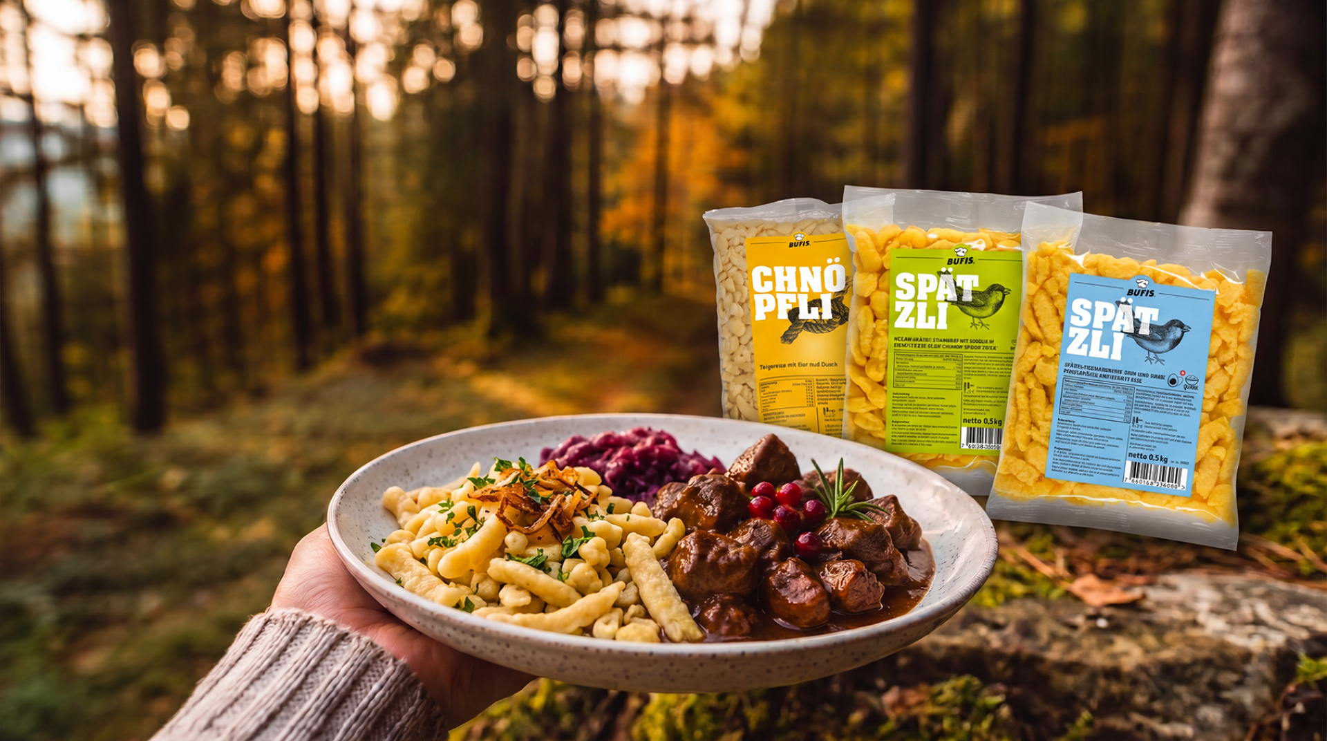 In einem Wald hält eine Hand einen Teller mit Spätzle, Rotkohl und Eintopf. Auf Moos liegen drei Tüten Spätzle, im Hintergrund sind hohe Bäume und warmes Sonnenlicht zu sehen.