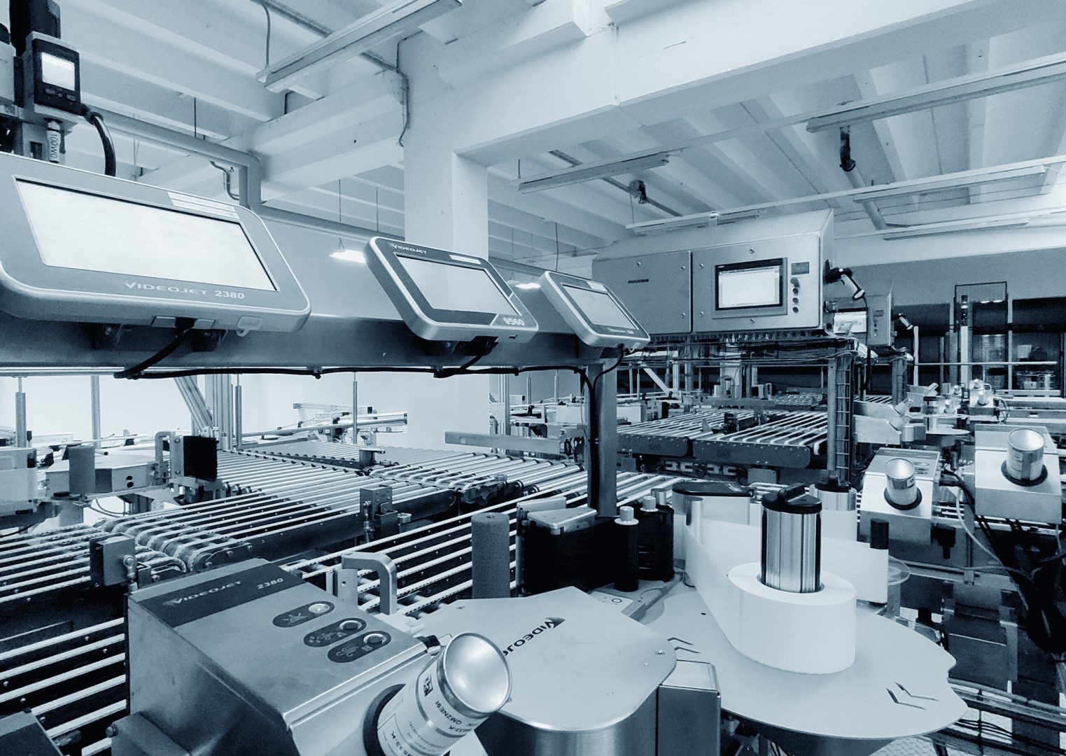 Automatisierte Maschinen in einer modernen Fabrik mit Förderbändern, Steuertafeln und Etikettiersystemen in einer großzügigen, gut beleuchteten Industrieumgebung.