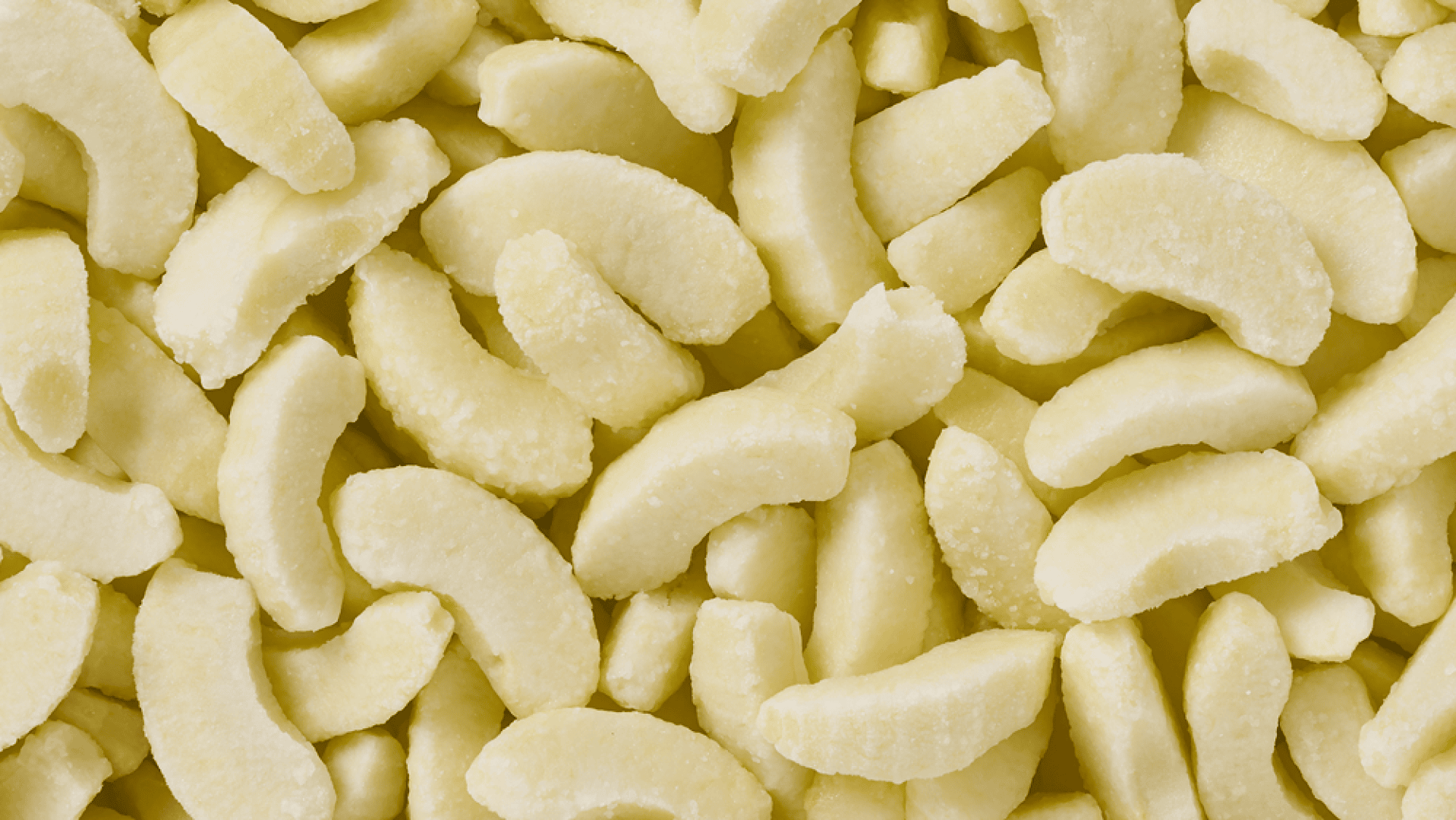 Nahaufnahme vieler gefrorener Apfelscheiben mit einer leichten Reifschicht, die in einem verstreuten Muster angeordnet sind und den gesamten Rahmen ausfüllen.