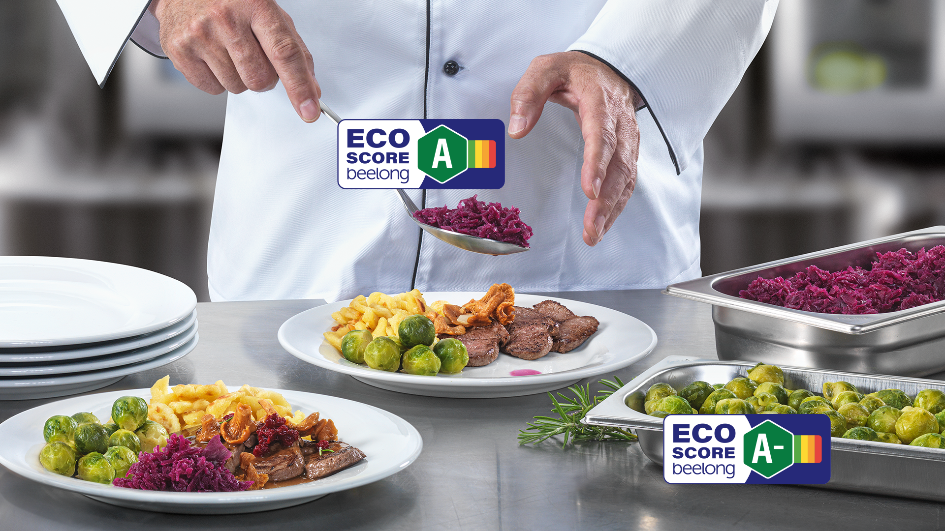 Ein Koch richtet ein Gericht mit Rosenkohl, Rotkraut, Späzli und Fleisch an. Zwei Eco-Score Labeles mit der Bewertung A und A- sind zu sehen.