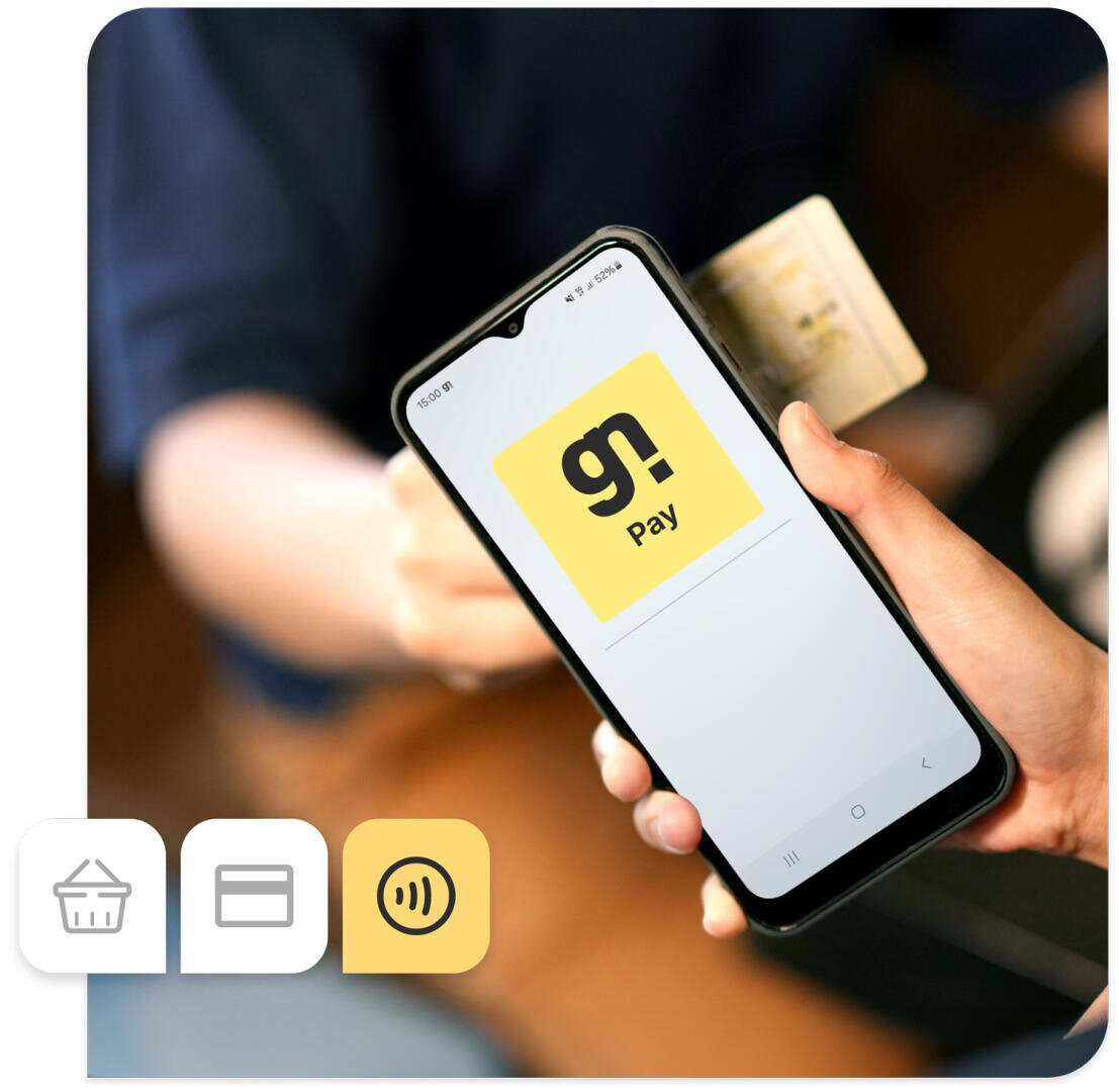 Eine Hand hält ein Smartphone, auf dessen Bildschirm die gelbe „go! Pay“-App zu sehen ist, während eine andere Hand eine Kreditkarte in das Smartphone einführt. Unten links sind Zahlungssymbole zu sehen.