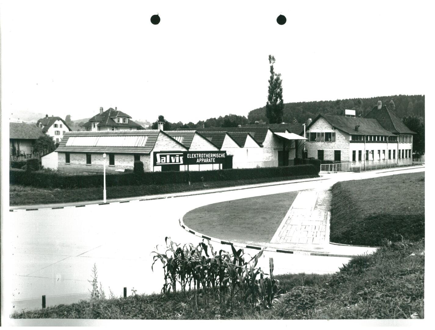 Ein Schwarz-Weiß-Foto des Salvis-Fabrikgebäudes, auf dem ein Schild mit der Aufschrift Salvis Elektrothermische Apparate zu sehen ist.