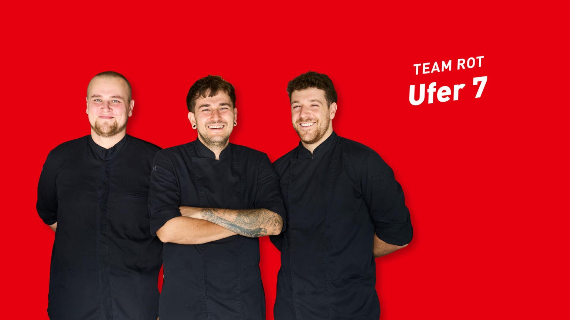 Drei Köche in schwarzen Uniformen posieren vor einem leuchtend roten Hintergrund mit der Aufschrift TEAM ROT Ufer 7.