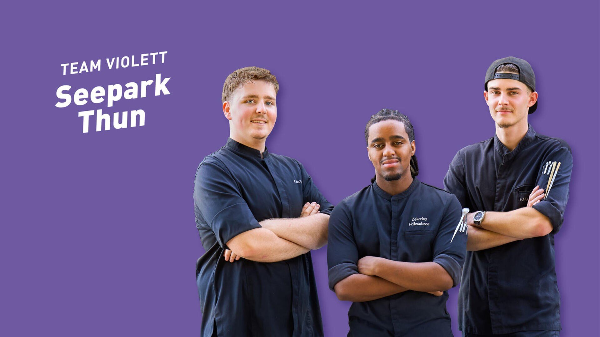 Drei Köche in dunklen Uniformen stehen vor einem violetten Hintergrund, auf dem die Aufschrift Team Violett Seepark Thun zu lesen ist.