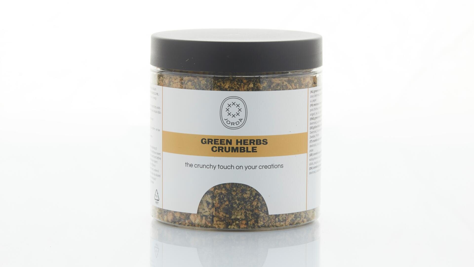 Ein durchsichtiges Plastikglas mit schwarzem Deckel enthält grüne Kräuterkrümel. Auf dem Etikett steht „GREEN HERBS CRUMBLE“ und „die knusprige Note für Ihre Kreationen“. Das Glas steht vor einem weißen Hintergrund.