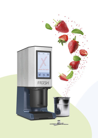 Neben einem Metallbecher, in dem Erdbeeren und Minzblätter schwimmen, steht ein elegantes FRXSH-Küchengerät – ein Hinweis darauf, dass gerade frische Zutaten gemixt werden.