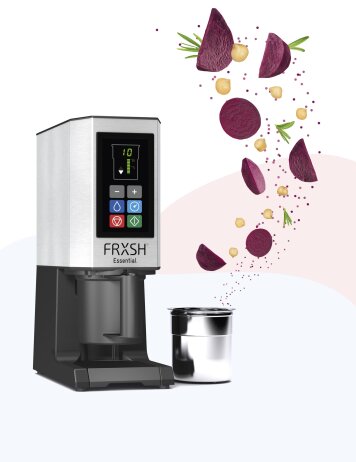 Neben einem Metallbecher steht ein moderner Getränkeautomat mit der Aufschrift „FRXSH Essential“; darüber schwimmen Rote-Bete-Scheiben, Kichererbsen und Kräuter, die auf frische Zutaten für ein Getränk hindeuten.